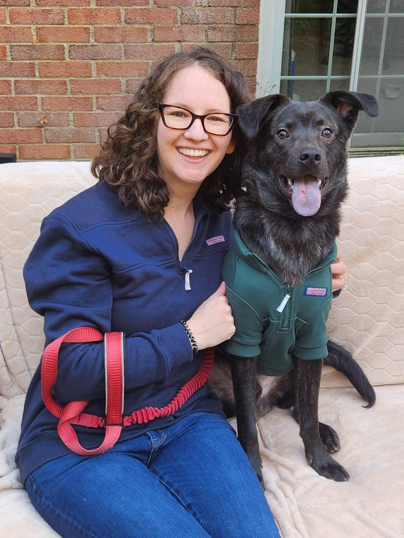 Woman with a black dog on a bench outside a building